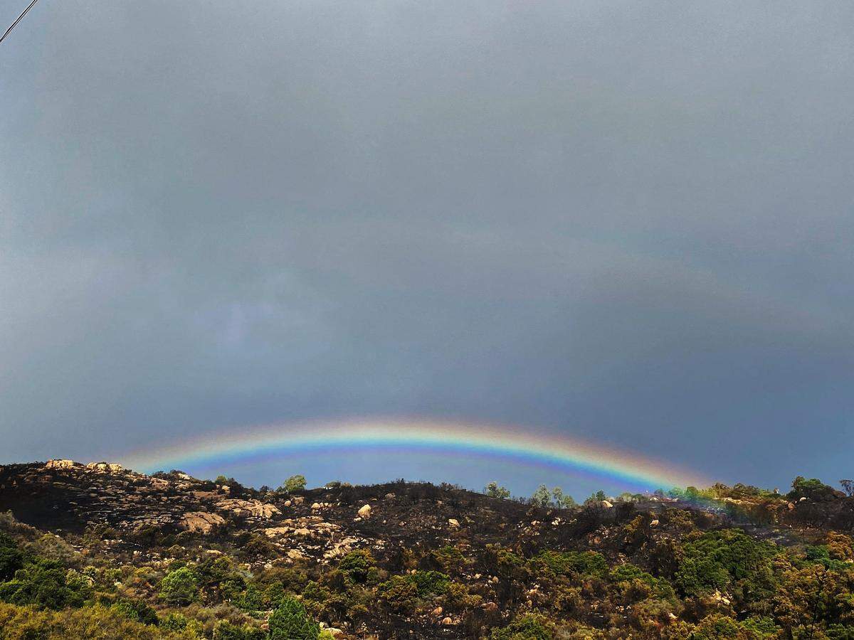 With small smokes still smoldering below, a rainbow appears above the burn scar near Painted Cave Road Wednesday morning.
