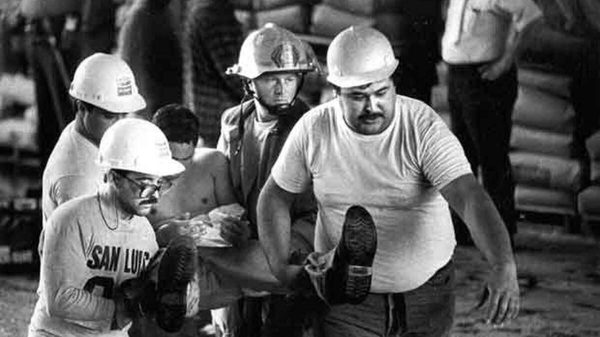 An injured sugar plant worker is carried to a waiting ambulance by co-workers and a firefighter. Three people were critically injured in the explosion at a Betteravia sugar refinery.