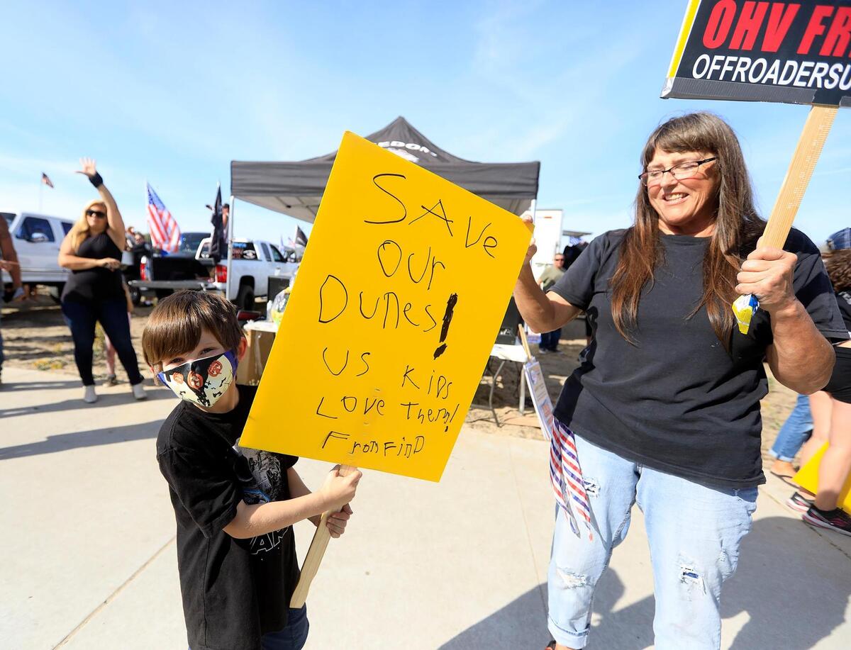 Finn Robinson, 7, Oceano, holds a sign with his grandmother, Cindy Morton, Grover Beach. Hundreds of off-road enthusiasts gathered for a Freedom Rally to open Oceano Dunes State Vehicular Recreation Area which was closed to vehicles during the coronavirus pandemic in October 2020.