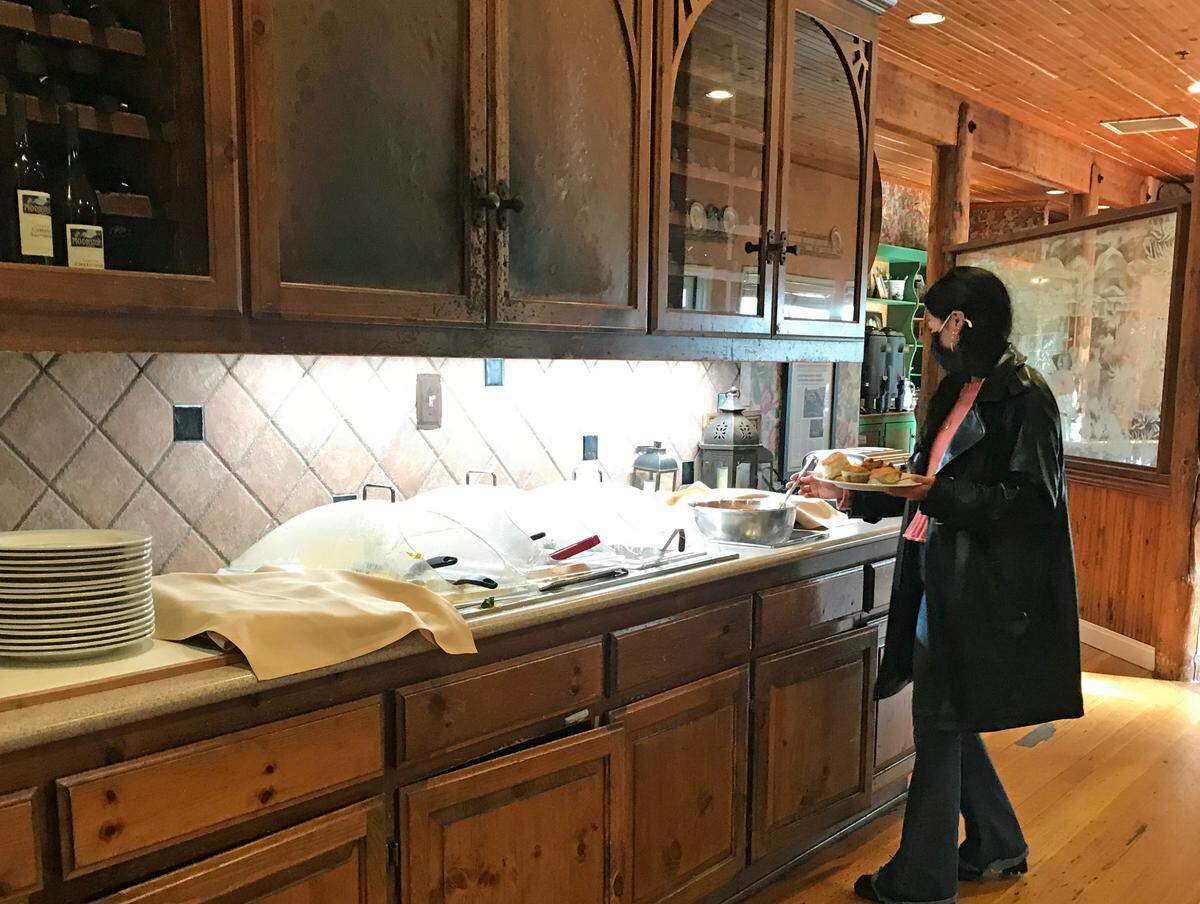 A guest at the Cambria Pines Lodge selects her breakfast items from one station of the hotel’s extensive breakfast buffet.