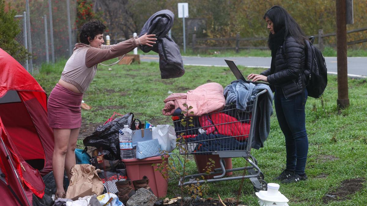 Ashlynn Miles throws her blankets into a basket on Friday as she talks to Sasha Aguilar, an attorney with California Rural Legal Assistance. Homeless camps on the Bob Jones Trail in San Luis Obispo were dismantled on Jan. 7, 2022, in advance of work along the creek to reduce fire risk, upgrade trail fencing and improve flood control.