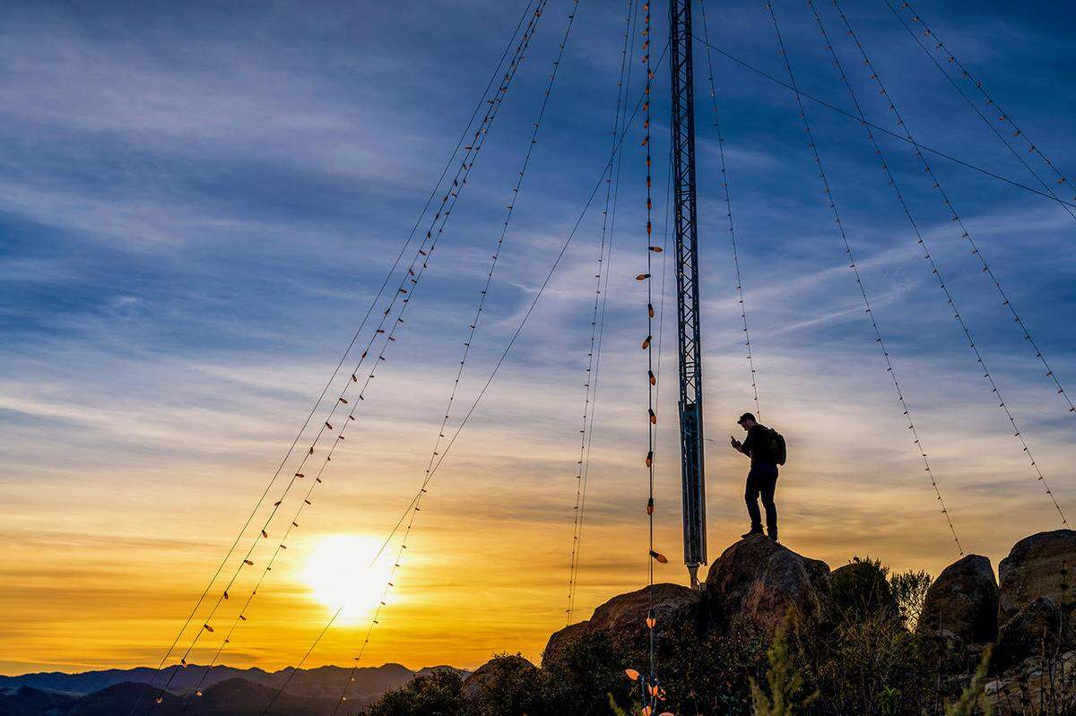 A hiker stands in the center of the Madonna Christmas tree on top of Cerro San Luis.