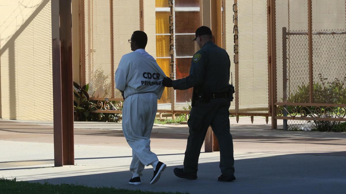 An inmate is moved under escort at the California Men’s Colony prison in March 2020.