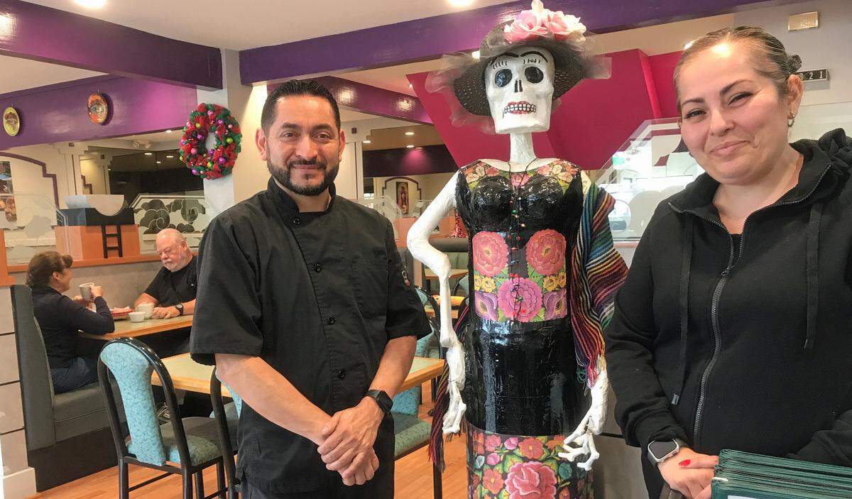 Co-owners Rafael Hernandez and Wendy Morales flank a Katrina sculpture in their new La Katrina Cocina restaurant in Morro Bay, while customers Bob and Ruthie Ashton of Los Osos tuck into their breakfasts at left.