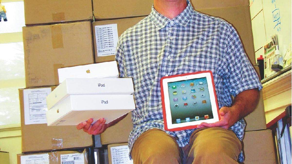 Coast Unified School District Technology Director Henry Danielson poses with boxes holding a shipment of 390 Apple iPad 2s.