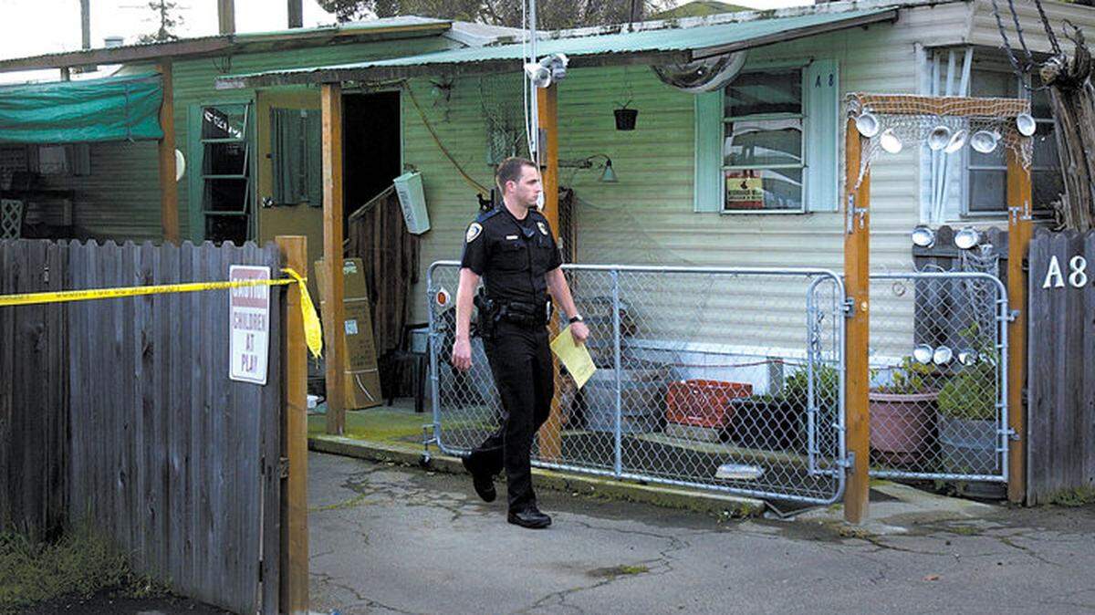 In this March 2005 photo, a San Luis Obispo police officer walks past the home of Gerald O'Malley, who was found dead inside by police.