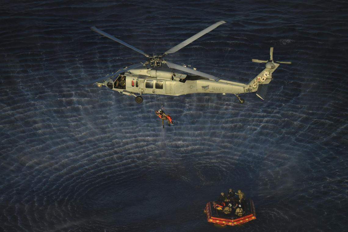 U.S. Navy divers and Artemis II astronauts aboard an inflatable raft are approached by helicopters and lifted away to the recovery ship after egressing NASA’s Orion spacecraft following splashdown in the Pacific Ocean near San Diego, California, on Friday, April 10, 2026.