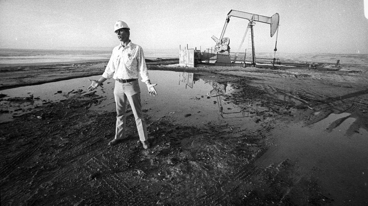 Dale Hick, a Union Oil Co. Foreman discusses work at Guadalupe oil field. A rainwater puddle reflects pumpjack in background. The company would later be known as Unocal. Photo is from Jan. 2, 1980.