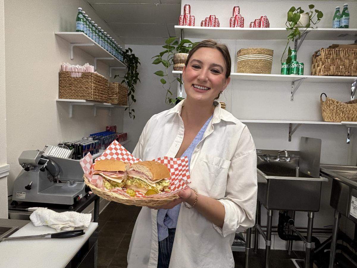 Owner of Swell Sandwich Shop Geneva Franciskovich holds up the fan-favorite Swell Sandwich. The shop opened April 23, 2026, and serves cold cut sandwiches, chips and soda.