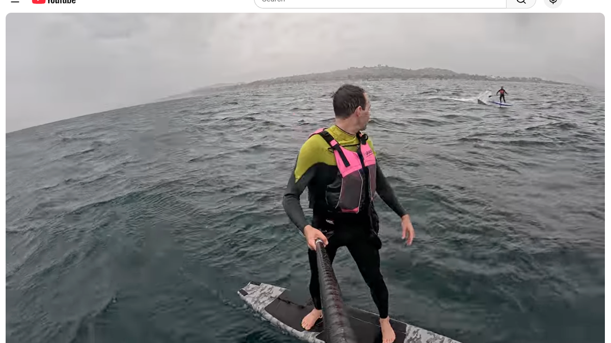 A foilboarder named Travis watches as a shark tails his friend, Ron Takeda, in the ocean along the coast between Santa Barbara and Carpinteria on April 26, 2026.