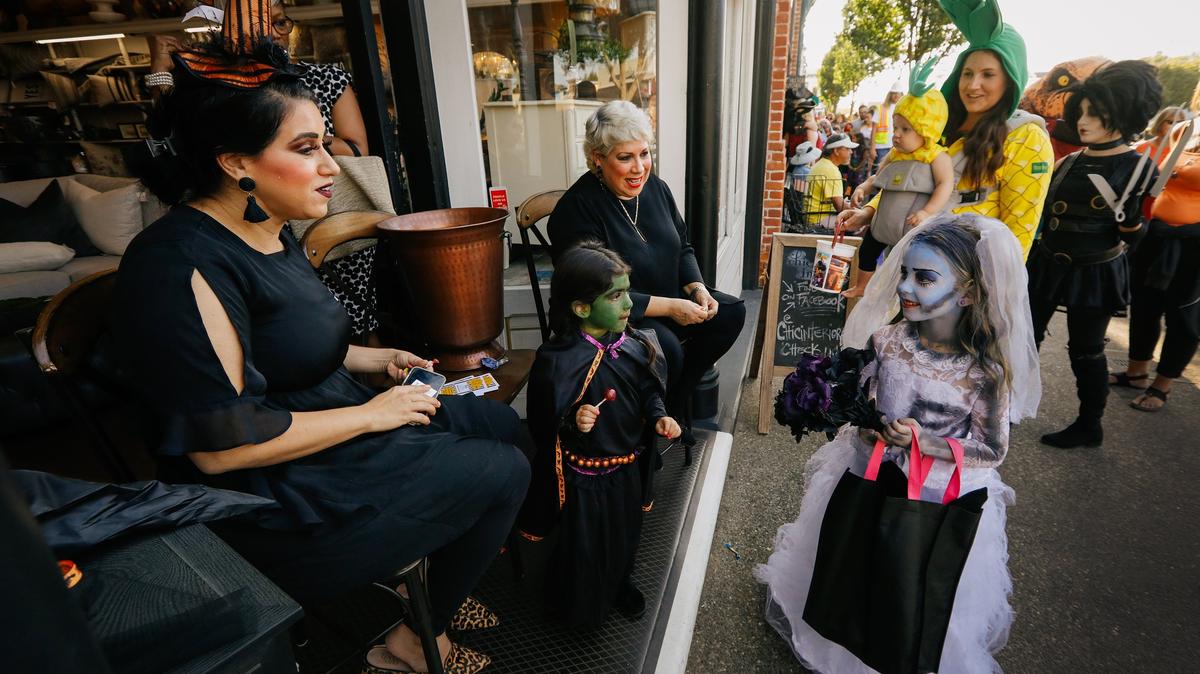 Gredsa Johnson, left, owner of Chic Interiors, her daughter Ciel, 3, and Johnson’s mother Sandra Olivas give out candy to trick-or-treaters during Halloween festivities in the Arroyo Grande Village in 2018.