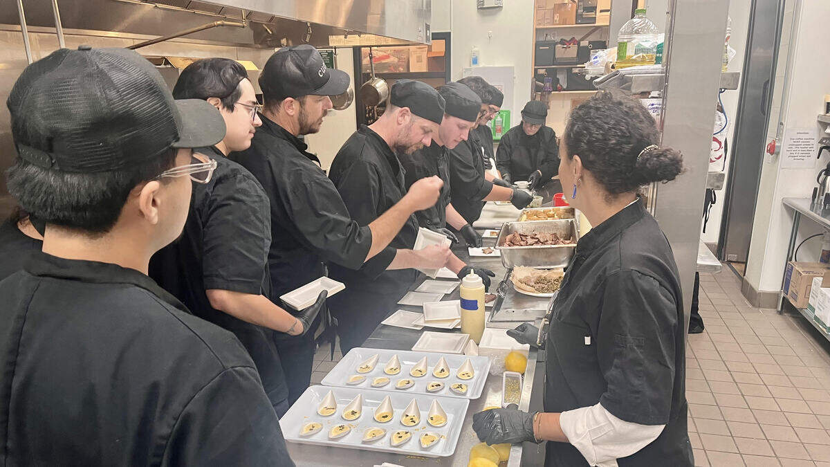 Cuesta College Culinary Instructors Graham Yates (left, in cap) and Zoe Elliott (right) assist students as they prepare food for their Jazz Night final project in downtown SLO.
