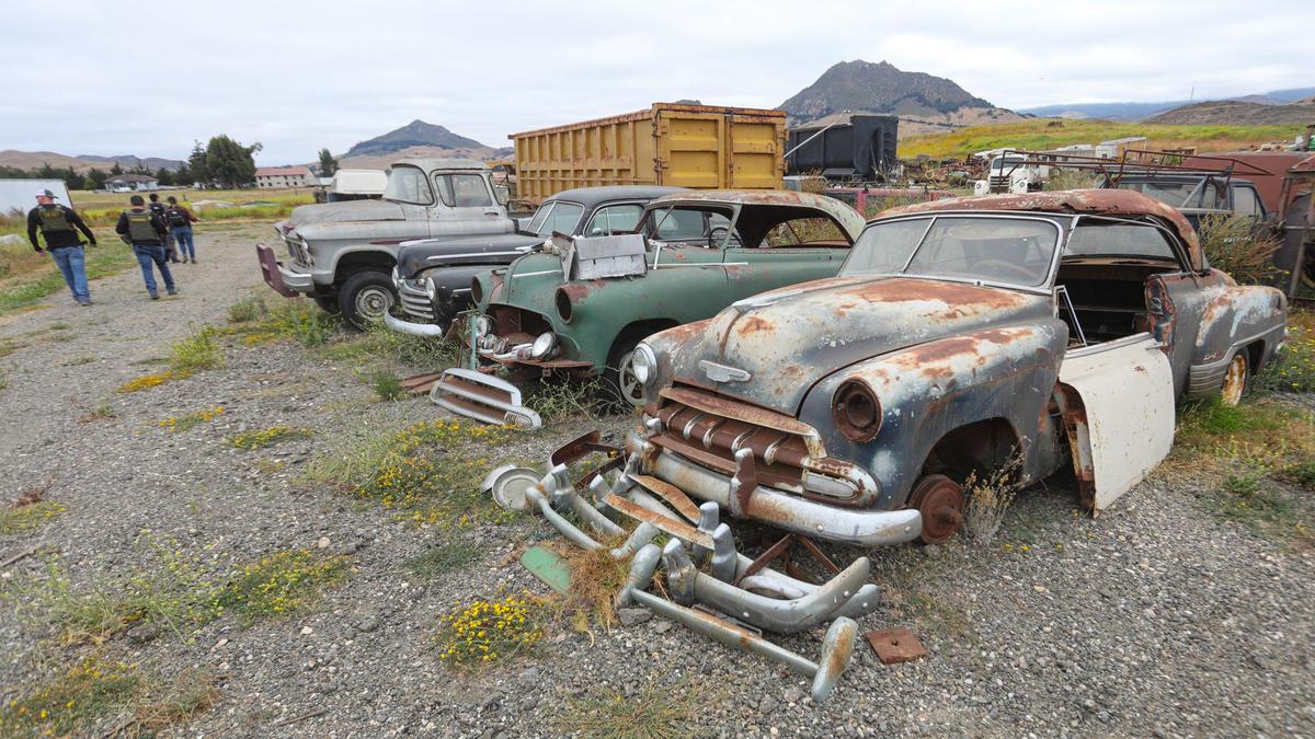 County code enforcement officers and other officials inspect Dan DeVaul’s Sunny Acres sober-living facility just outside San Luis Obispo on Wednesday morning, June 23, 2021. Various broken-down vehicles are stored on the site, including classic cars like these.