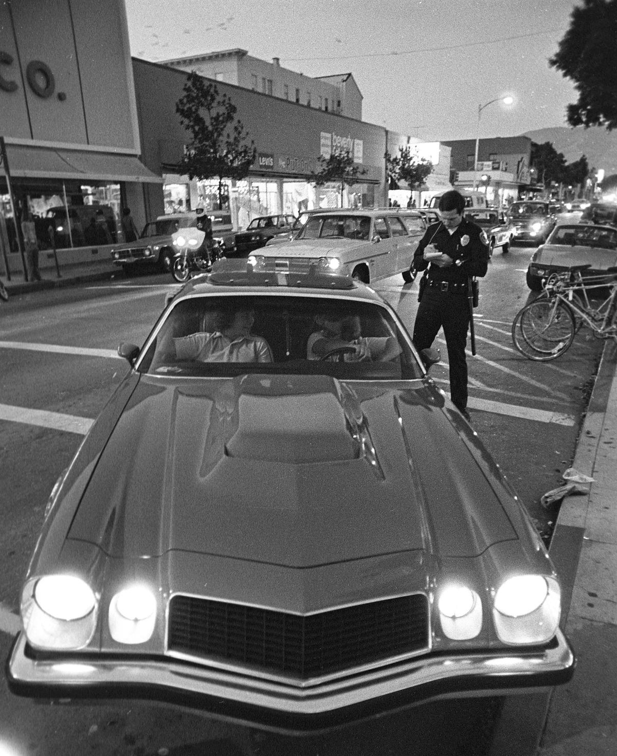 San Luis Obispo police officer Robert Quinlan issues a citation for improper lighting during the last cruise night in San Luis Obispo on July 3, 1980
