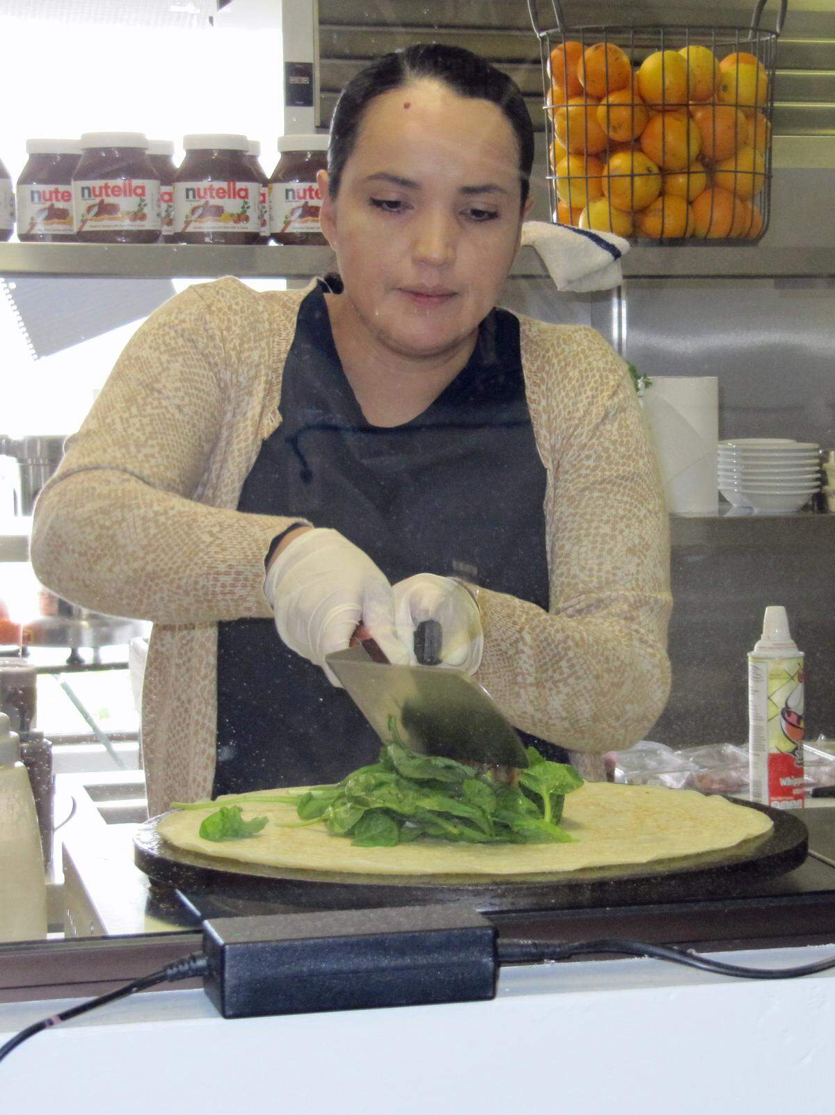 As seen through the demonstration window at The Spot restaurant, MaryLyn Reveles creates an oversized mushroom-spinach crepe.