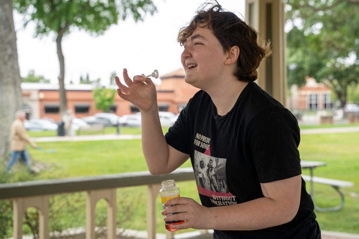 Paso Robles High School Queer Student Union president Aster Watson blows bubbles at Downtown City Park in Paso Robles on Saturday, May 2, 2026. The Queer Student Union offers community to LGBTQ+ students through after-school events such as a clothing swap held in the park.