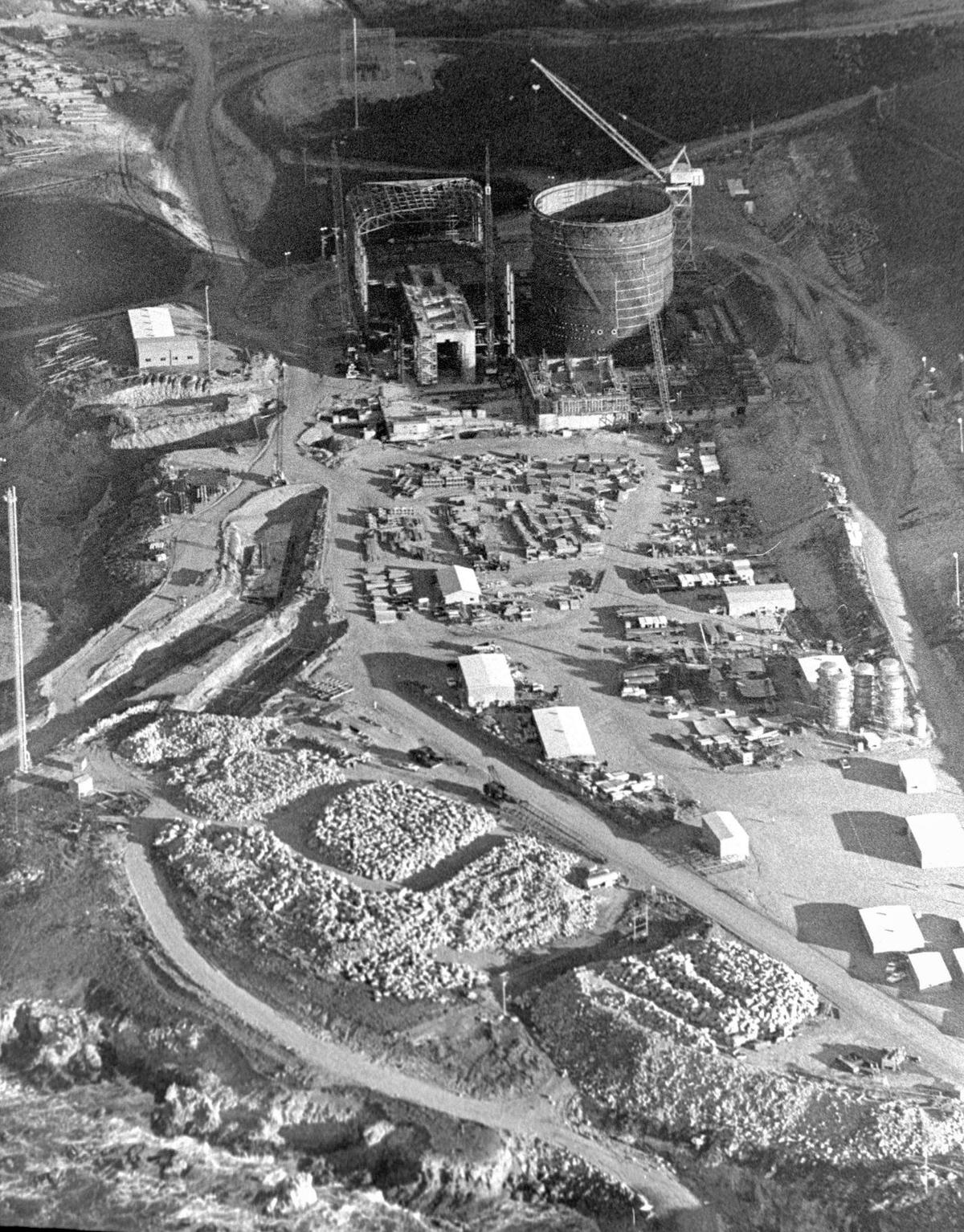 The PG&E Diablo Canyon nuclear-fueled power plant rises steadily on the San Luis Obispo County shoreline. Round reactor structure is in upper right. Stockpile of rock in foreground is for breakwater construction on March 5, 1971.