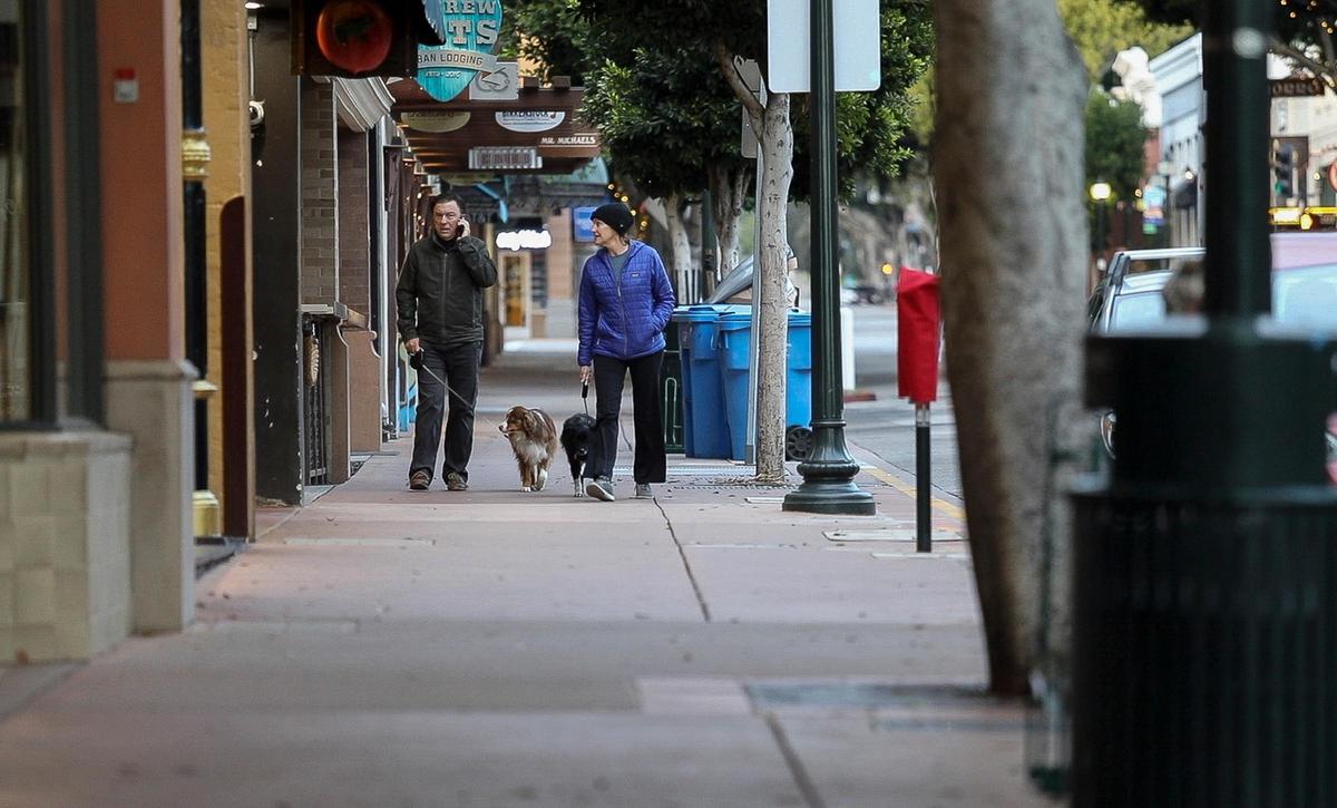 The usually busy streets in downtown San Luis Obispo were virtually empty Thursday night after the county’s shelter-at-home order went into effect at 5 p.m. Two people walk their dogs with no one else about on Higuera Street.