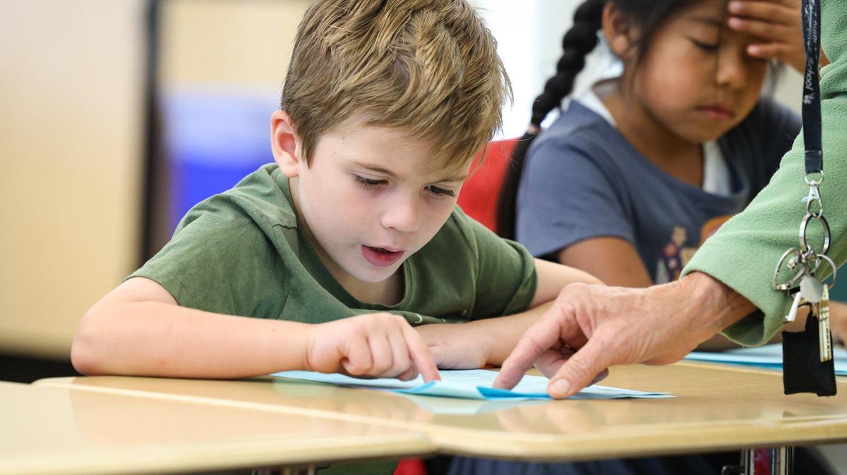 First-graders Oliver Hootman and Eva Jimenez Flores practice reading word by word at Carrisa Plains Elementary School with help from Jani Klasfeld, in September 2023.