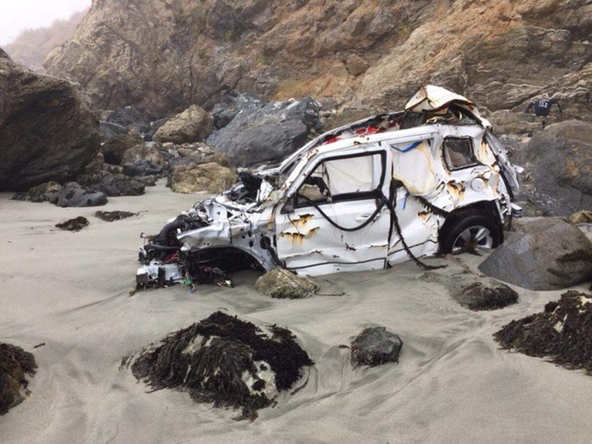 The wreck of Angela Hernandez's white 2011 Jeep Patriot rests in the water line Friday on a rocky Big Sur beach.