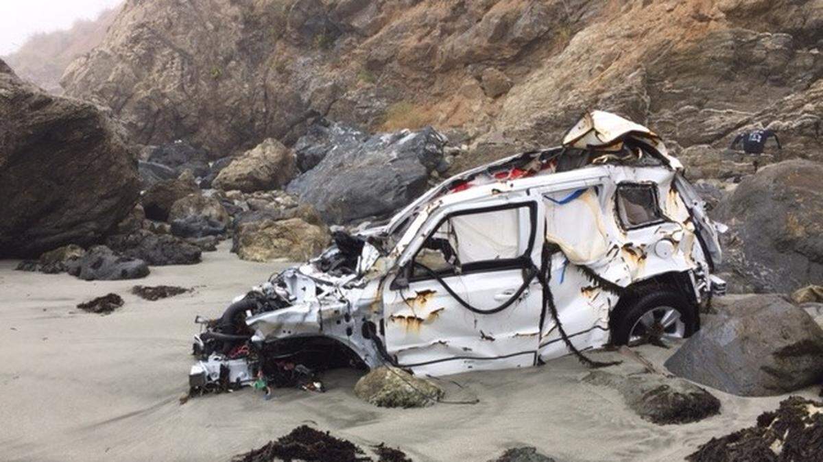 The wreck of Angela Hernandez's white 2011 Jeep Patriot rests in the water line Friday on a rocky Big Sur beach.