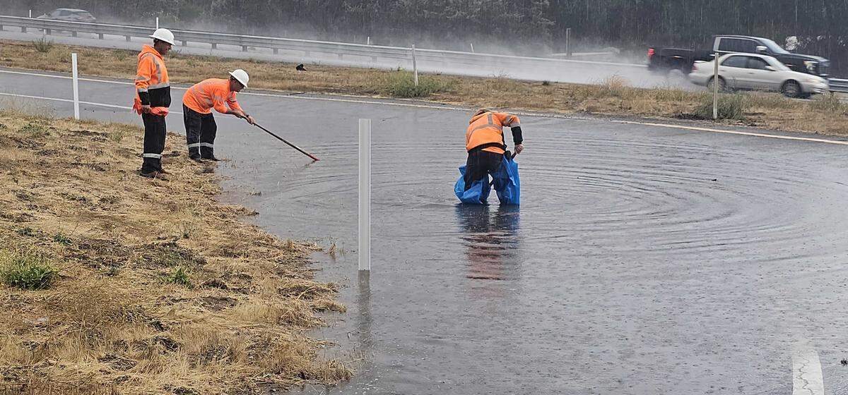 Caltrans employees work to clear the flooded the southbound San Ramon Road exit from Highway 101 in Atascadero on Oct. 14, 2025.