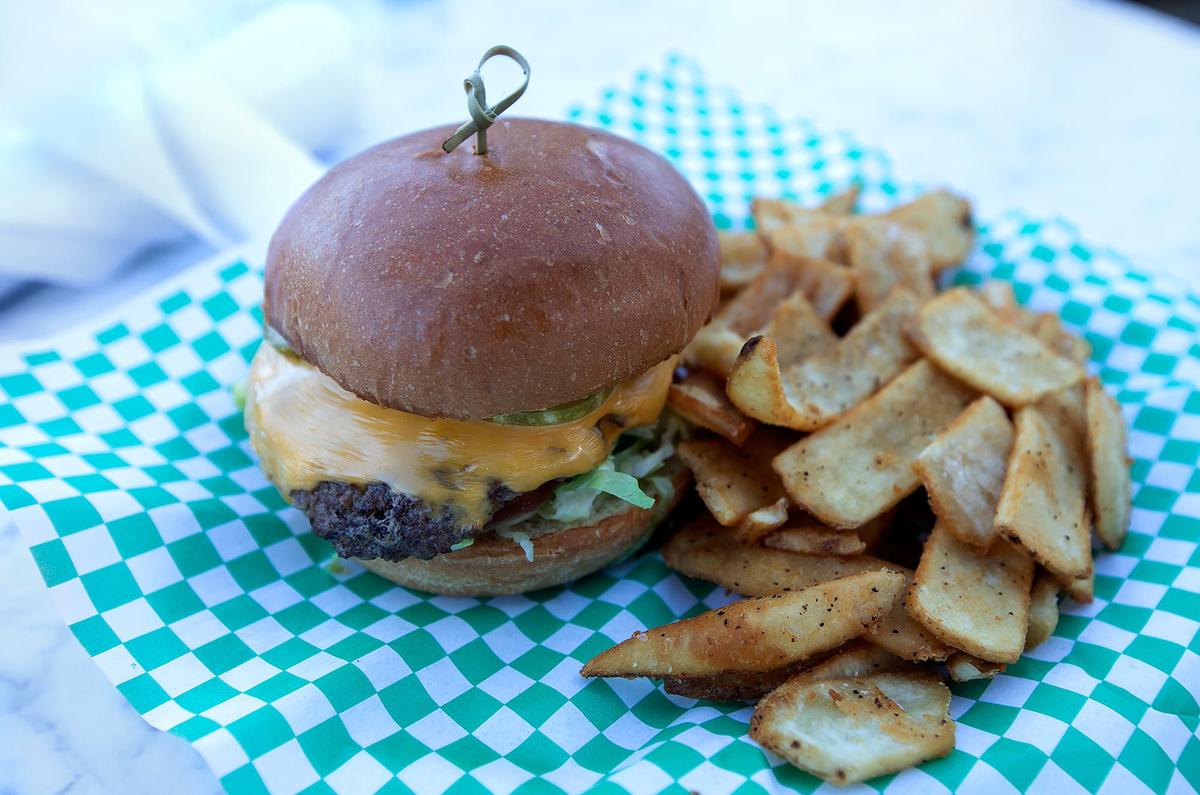 The Pig Iron restaurant’s Niman Ranch Beef Smashburger is served with American cheese, iceberg lettuce, tomato, caramelized onion, aioli, house pickles on a brioche bun.