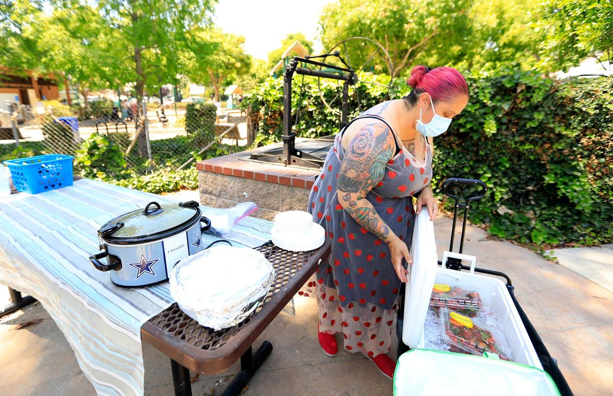 Michelle Mansker, a founding member of SLO Street Medics who works to help the homeless community, sets up a table in Mitchell Park with a chicken curry stew, salad, fresh fruit and water. She also provides hygienic supplies and clothing. The city of SLO is working toward a 2-year strategic homeless response plan.