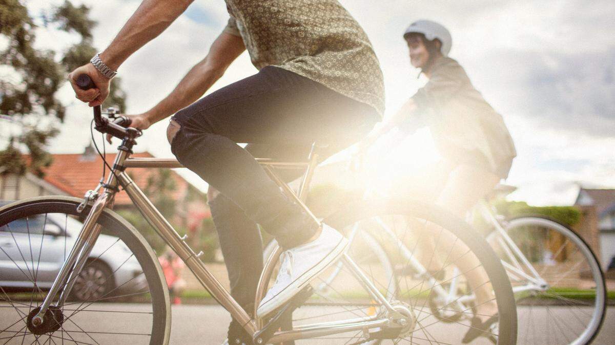 Cyclists ride down a street on a sunny day.