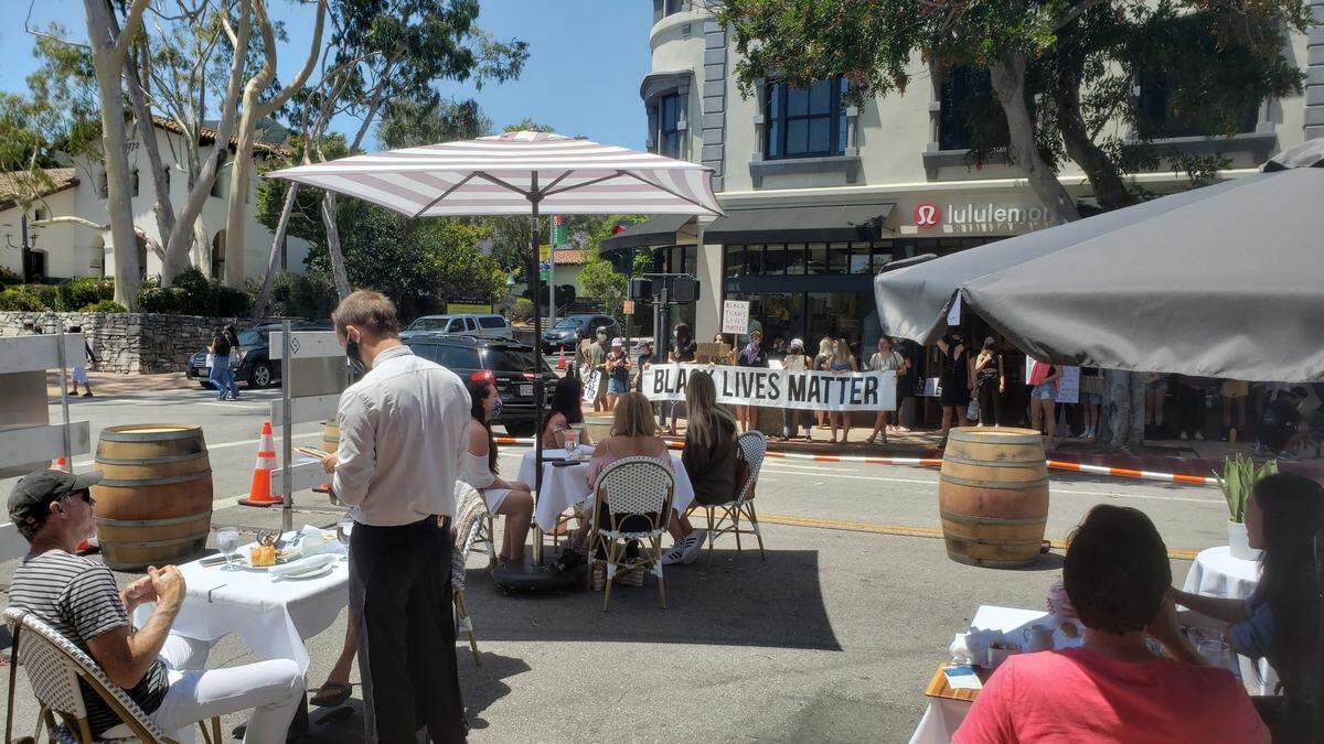 Protesters line up along businesses surrounding Giuseppe’s and Finney’s outdoor dining parklets during Saturday’s demonstration in San Luis Obispo. They remained silent and stayed out of the doorways of businesses.