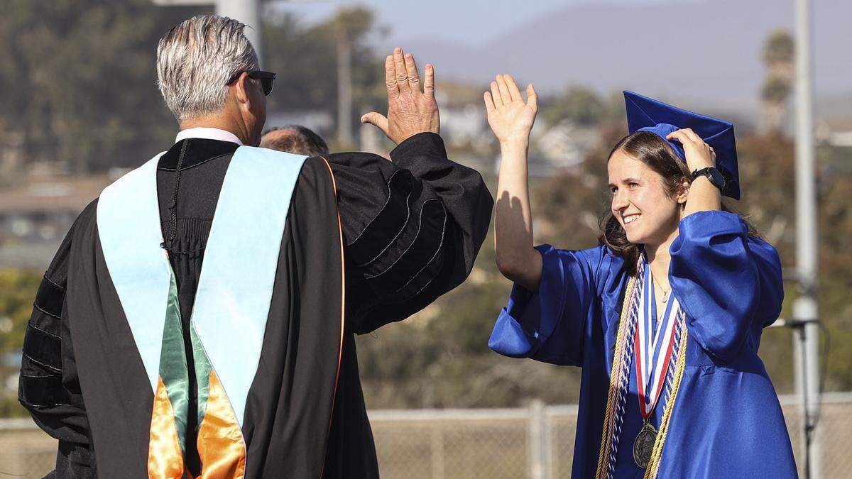 Valedictorian Margaret Appel gives high fives to administrators. Morro Bay High School issued diplomas to 176 graduates on June 4, 2026.