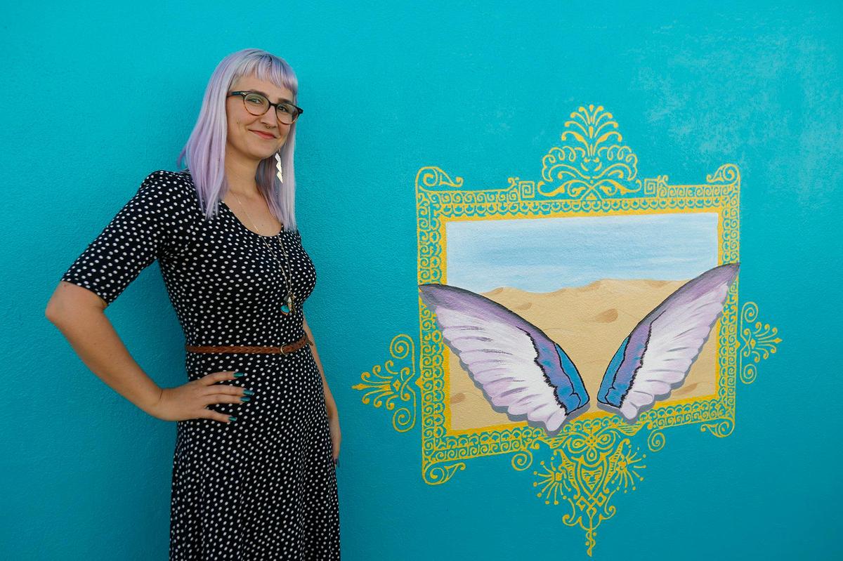 Artist Krista Jeffries stands in front of the painting she did for the “selfie wall” located on the back of the First Class Seconds building located at 141 N. 6th St.