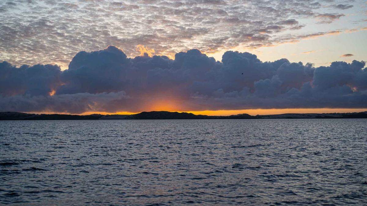The sun setting behind dense clouds over Morro Bay.