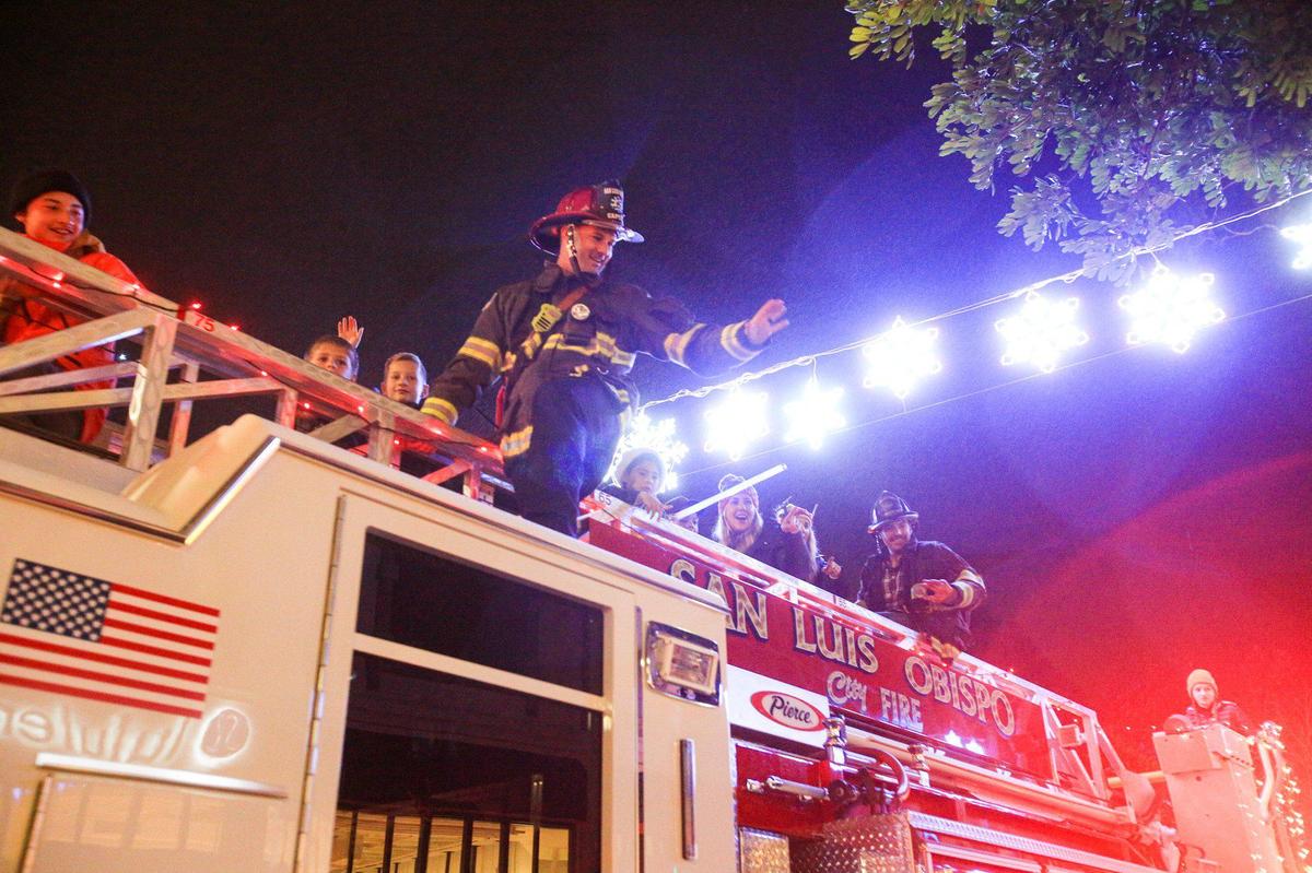 Alec Flatos, fire engineer and paramedic with SLO City Fire department, waves to the crowd from atop an engine. The 46th annual Holiday Parade, under the theme “Rockin Retro Holidays,” took to the San Luis Obispo streets Dec. 2, 2022.