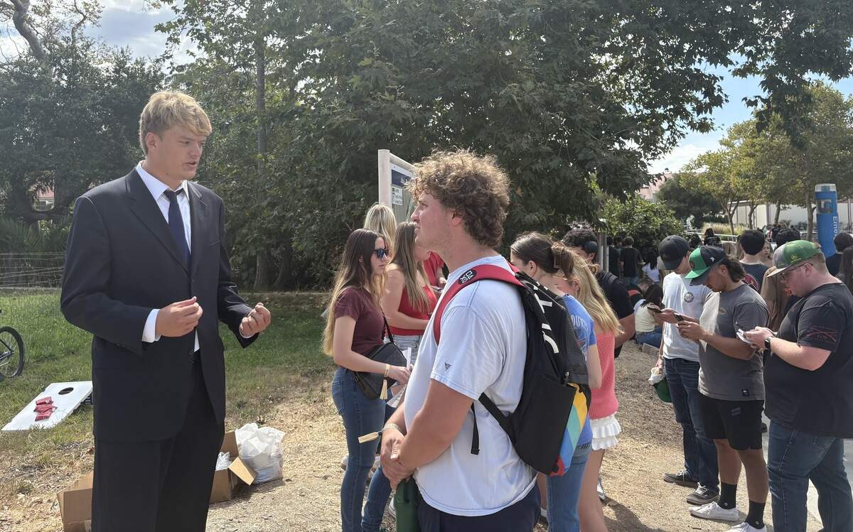 Turning Point USA chapter president Ryan Rundle speaks with a visitor during Cal Poly’s Week of Welcome club fair on Sept. 17, 2025. The club did not have a booth at the event but set up on the corner across from the lot where it was held.