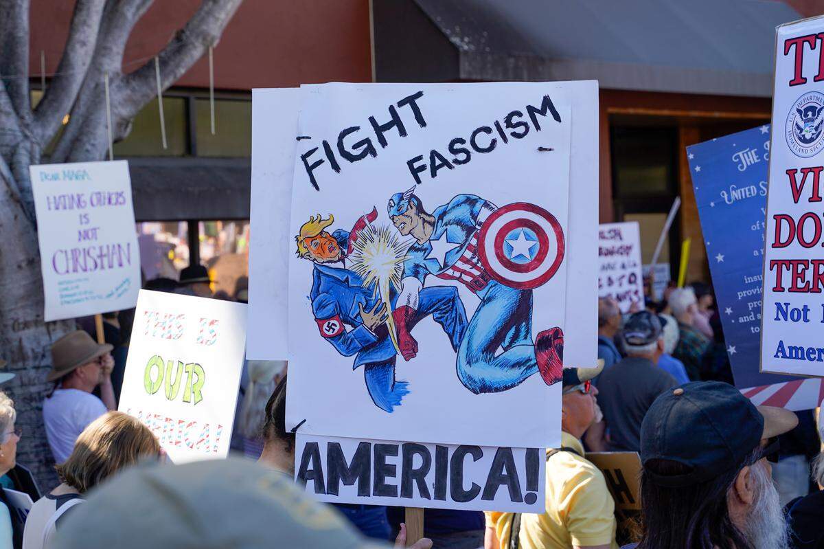 A sign shows Captain America knocking out Donald Trump at the No Kings protest in San Luis Obispo on Saturday, March 28, 2026. Organizers estimated around 2,500 people attended the San Luis Obispo protest, with more in Atascadero, Cambria and Grover Beach.