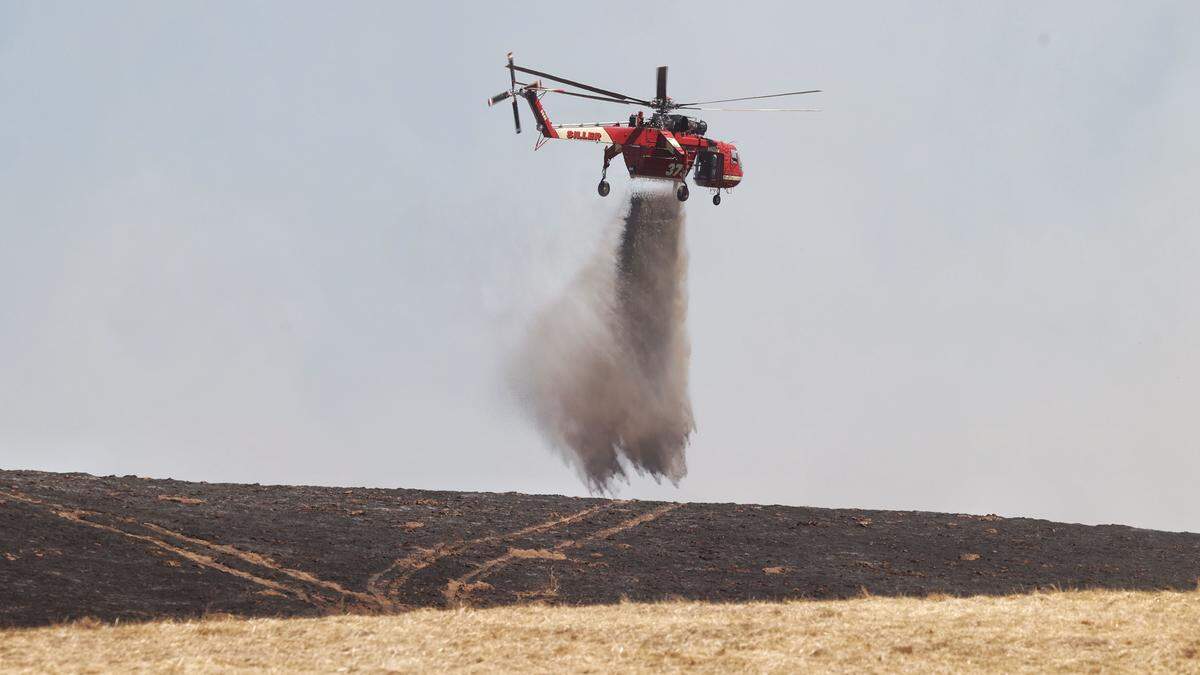 A helicopter drops retardant on a vegetation fire that broke out in Atascadero on Aug. 18, 2025, and burned 40 acres near an elementary school.