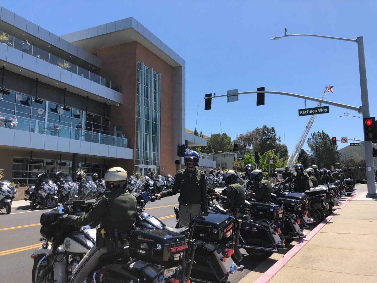 Dozens of armored cars, motorocycles and police cars began lining up along Grand Avenue shortly after the memorial service for slain San Luis Obispo Police Det. Luca Benedetti.