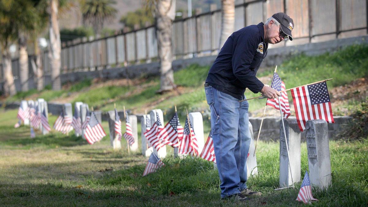 U.S. Navy veteran Greg Somers places American flags in 2020 along with other volunteers marking Veterans Day at San Luis Cemetery.