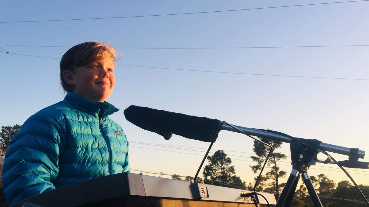 Koa Crampton, a Kerry Street neighbor, sings “Here Comes the Sun” from the rooftop home of Steve and Lori Kniffen in Cambria on May 1, 2020.