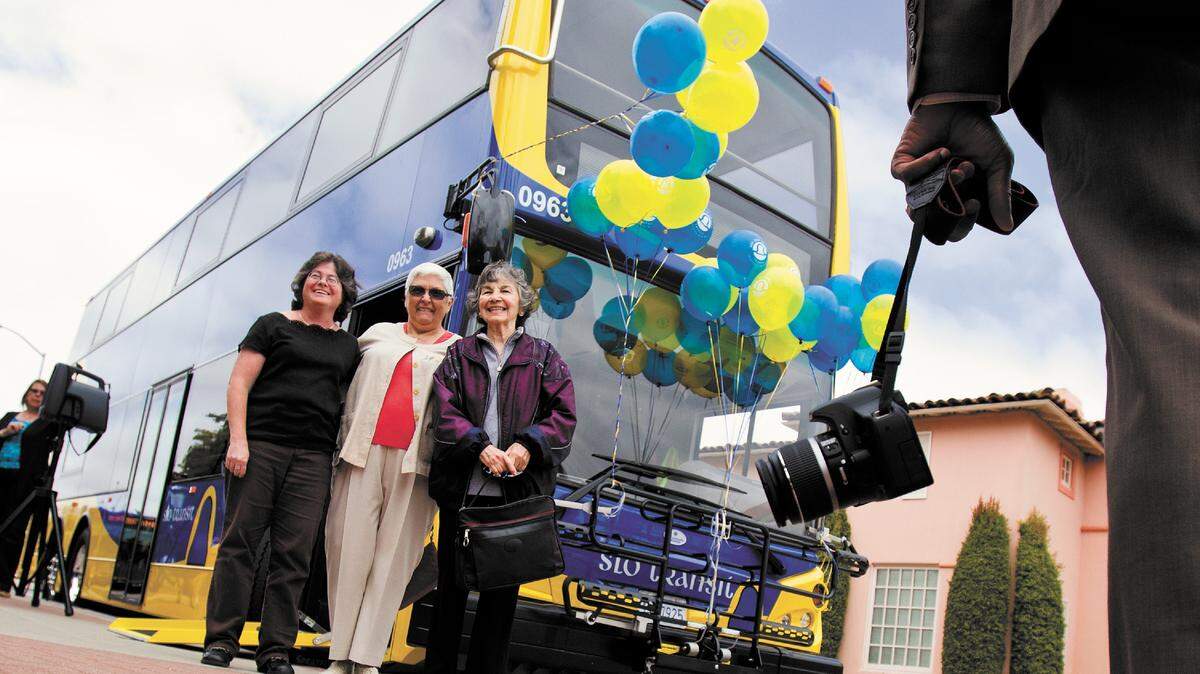 Denise Martinez, left, and Louise Justice, center, both on the mass transit committee, pose with Evangelina Moreno, frequent bus rider, in front of the new double-decker bus.