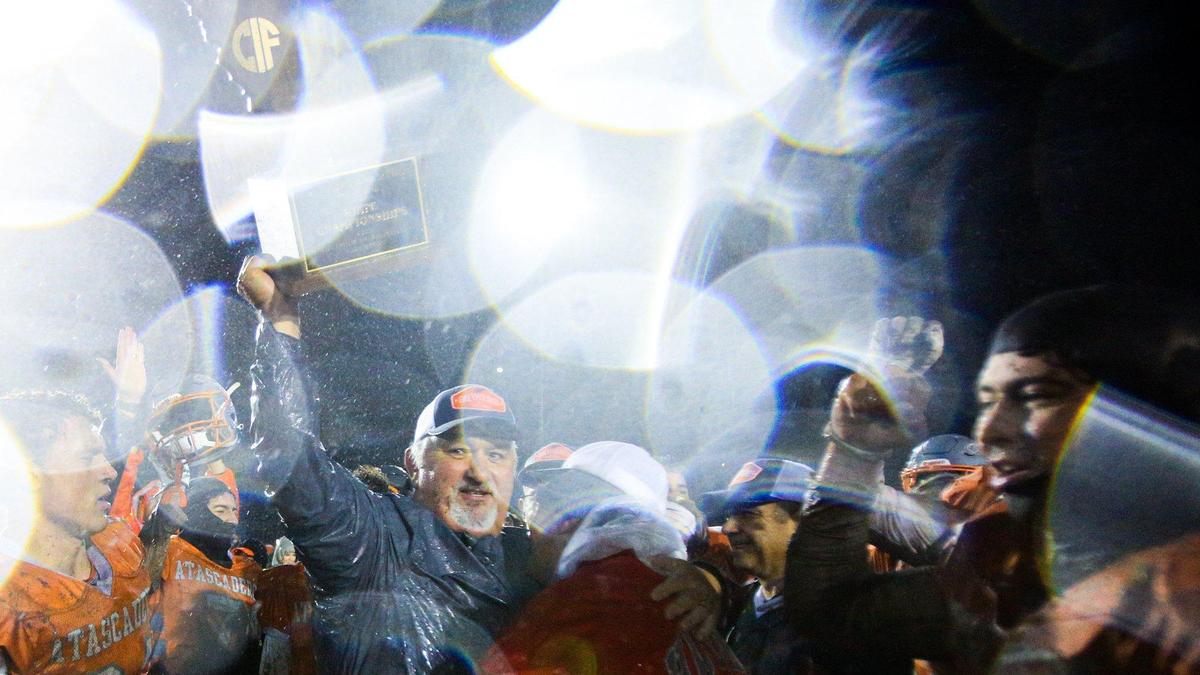 Head Coach Vic Cooper holds state championship trophy as rain falls after the Atascadero Greyhounds beat the San Gabriel Matadors 41-0 in the CIF Division 6-A State Finals football game in Atascadero on Dec. 10, 2022.
