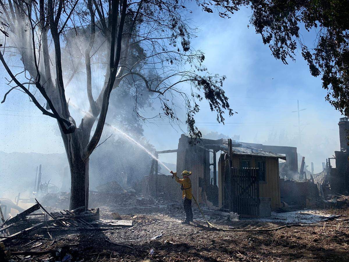 Firefighters hose down a house that burned on Creston Road in Paso Robles after a fire that started in the Salinas Riverbed jumped into nearby neighborhoods.
