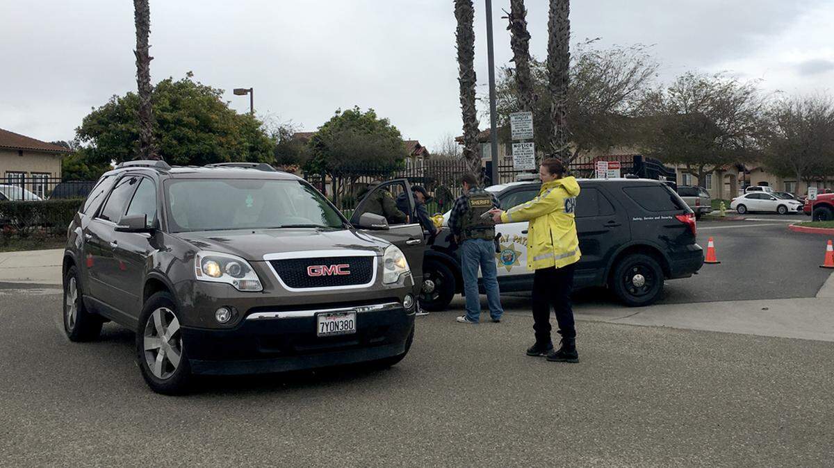 A vehicle is searched at gunpoint Tuesday afternoon in Guadalupe as law enforcement look for three suspects in a shooting that sent one man to the hospital. The driver was subsequently released.