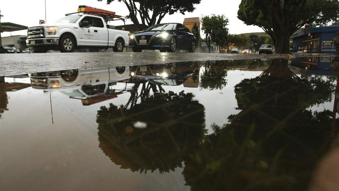 Traffic is reflected in a puddle over a backed up drain at the corner of Marsh and Carmel Streets in San Luis Obispo. A late season storm soaked San Luis Obispo County on April 21, 2026.