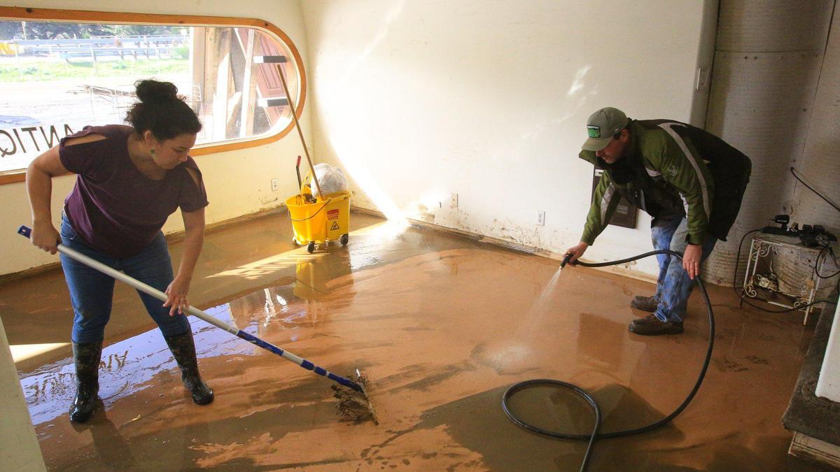 Rebecca and Chris Jules clean mud from the inside of Morro Bay Antiques on Jan. 10, 2023. More than a foot of muddy water flooded the store in Monday’s storm.