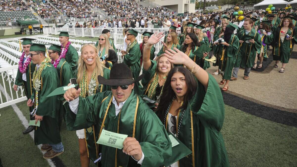 Vince Brooke in cowboy hat and Macey Adison at right were among the soon to be graduates walking into the College of Agriculture, Food and Environmental Science ceremony. Cal Poly held the first of six graduation ceremonies at Spanos Stadium on June 13, 2026.
