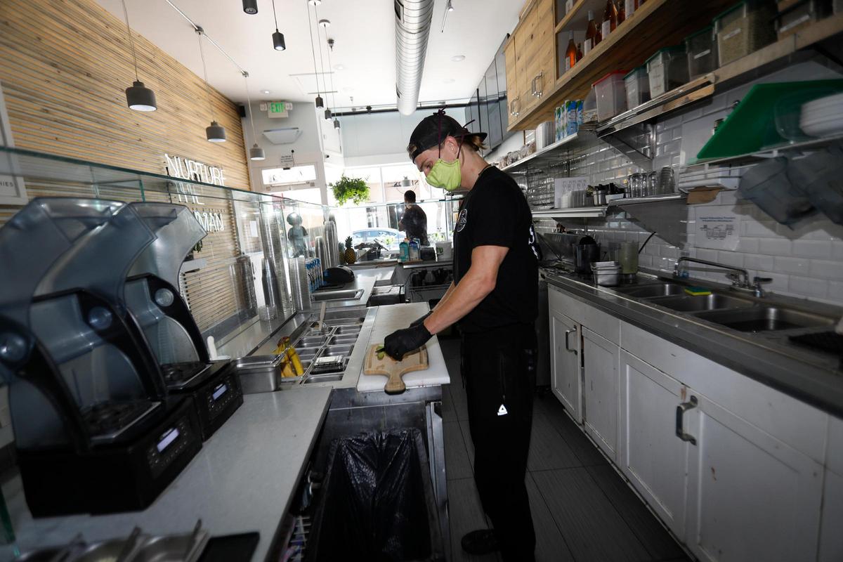 Downtown San Luis Obispo restaurants and businesses are among those operating during the pandemic. Seed’s general manager Everett Marr makes an order while properly wearing gloves and a mask.
