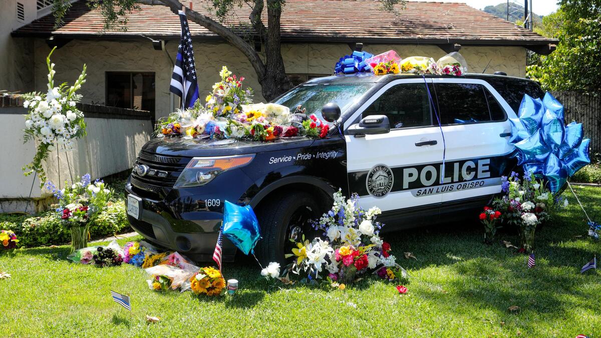 The San Luis Obispo police department parked a patrol car outside the police station as a gathering point for people who want to drop off flowers in support of the department after the death of Det.Luca Benedetti and wounding of Det. Steve Orozco during a warrant search last week.