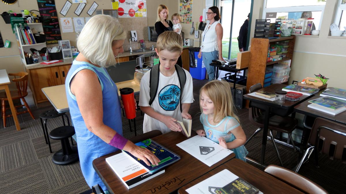 Gail Seminara, an instructional aide at Santa Margarita Elementary School, shows Tristan Pullen, 9, where he will sit for fourth grade while sister Belle, 5, checks out what upper grades look like. Atascadero Unified was the first district to head back to school in 2019.